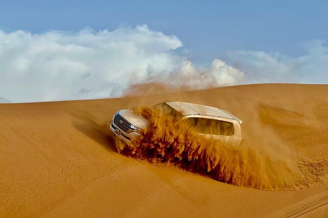 Dubai Desert Safari: Dune Bashing, Camel Ride, Sandsurf & 5<em> BBQ – Key details to know before booking’ /></p>
<ul>
<li><strong>Lahbab’s red dunes provide the main thrill:</strong> The safari heads beyond the city for a longer dune-bashing ride, with a sandboarding and photography stop along the way.</li>
<li><strong>Your driver matters:</strong> Ahmed has been praised for checking on passengers throughout the drive, while Ali helped with photos and made the desert outing feel welcoming.</li>
<li><strong>The $27.91 price covers a lot:</strong> Transport, dune bashing, sandboarding, camel activities, drinks, entertainment, and a barbecue buffet are all included.</li>
<li><strong>The camp is shared:</strong> You get a wide selection of activities, but this is not a private desert retreat. The vehicle and camp are shared, and the stated maximum is 100 people.</li>
<li><strong>Extra costs are easy to spot:</strong> Quad bikes cost $50, while shisha, alcohol, and a VIP table are not included.</li>
<li><strong>Plan for a six-hour outing:</strong> Pickup, the Lahbab stop, the camp visit, dinner, shows, and the return drive fill most of an afternoon and evening.</li>
</ul>
<h2 id="why-lahbab-is-the-right-place-for-the-action">Why Lahbab is the right place for the action</h2>
<p><img width="669" height="446" decoding="async" src=